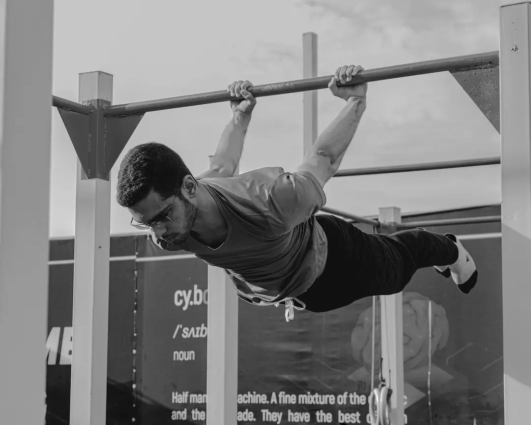 A Cyborg athlete holding a front lever in front of the cy·borg definition wall
